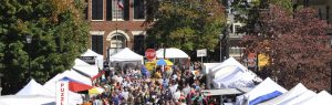 A photograph of people walking the dahlonega square at gold rush. Tents and vendors can be seen all throughout the square, with swarms of people in their fall clothes.